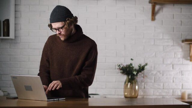 A young sound producer reading song text and turn on music using notebook. Man feels inspired when listening rhythmic music and texting friends. A young guy dancing, singing when writing text for his