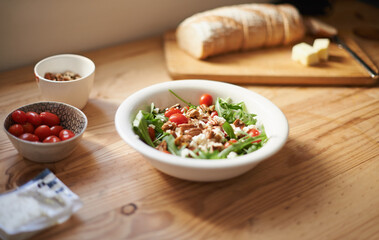 Healthy, salad and lunch on table in kitchen closeup with bread for nutrition and diet in home. Tomato, lettuce and cooking with nuts in food with bowl on counter for dinner and meal prep in house