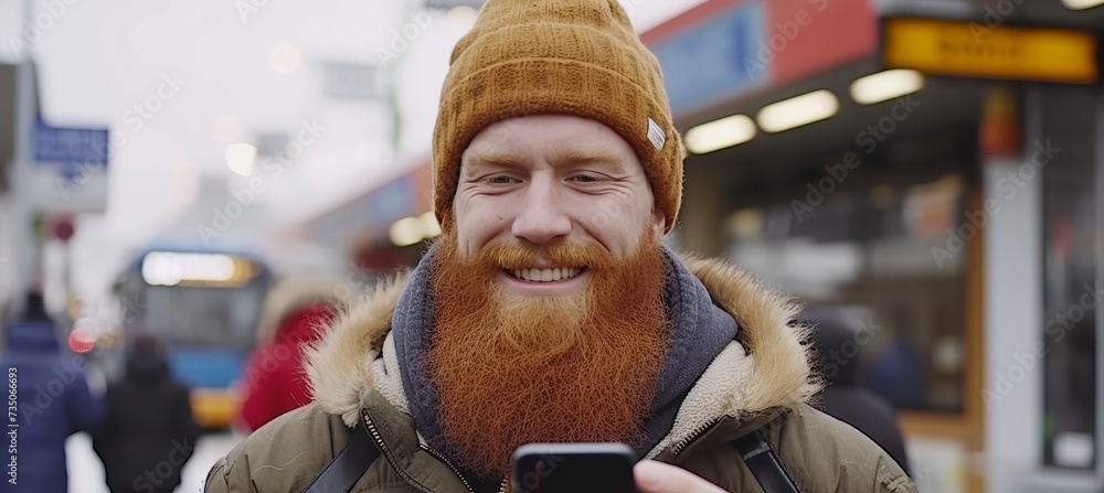 Poster bearded man smiling while using smartphone at bus station, with copy space for text placement