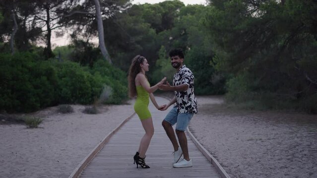 A couple of bachata dancers moving the hips on a footpath