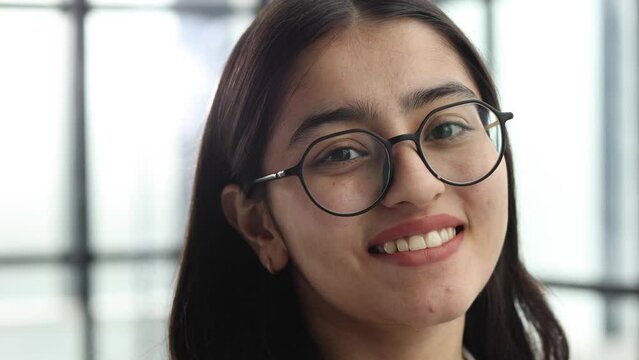 The face of a young successful woman in close-up with glasses in the office