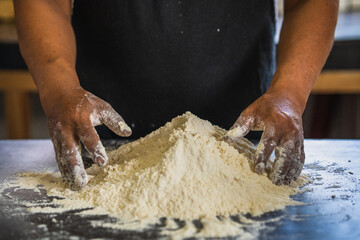 Baker's hands ready to knead a mound of flour, isolated on black background. prepares bread in the...