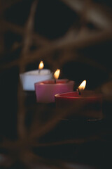 Close-up of three heart-shaped candles lit in the dark.