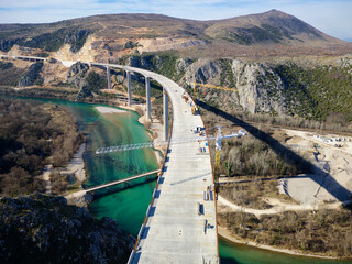 Aerial drone view of the construction of a high concrete bridge over the river. Highway bridge...