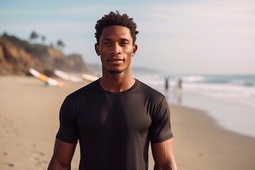 
young professional black surfer man, holds his surfboard in arm stands on ocean beach