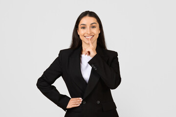 Confident young businesswoman with secret gesture