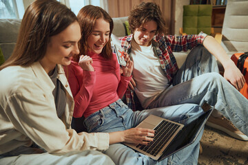 Young smiling people using computer for online reservation, buying tickets and booking hotels via...