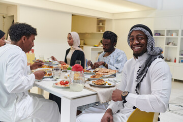 Fototapeta na wymiar A traditional and diverse Muslim family comes together to share a delicious iftar meal during the sacred month of Ramadan, embodying the essence of familial joy, cultural richness, and spiritual unity