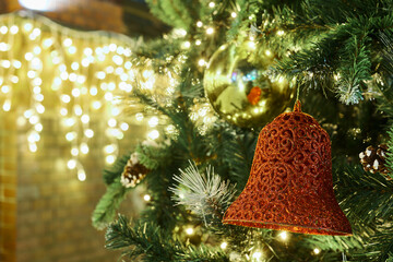 Festive New Year Christmas tree with red bell with garlands lights, close up view copy space, merry...