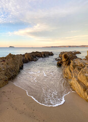 Beach at sunrise. Dawn on the beach. Waves curling on the rocky shore. Ocean view at low tide at sunset.	