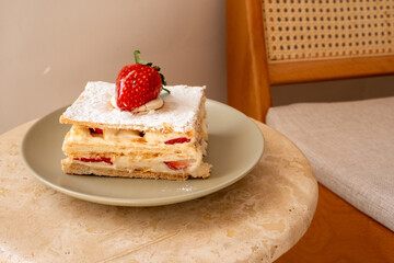 Strawberry tart on khaki green plate in restaurant with sun reflection
