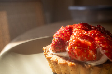 Strawberry tart on khaki green plate in restaurant with sun reflection
