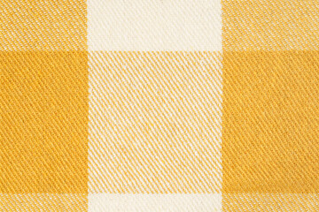 close-up texture of warm fabric for clothing of mustard yellow color in a tartan cell. Image for...