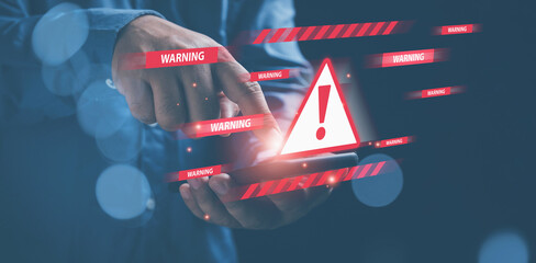 Businessman holding a smartphone turn on with triangle caution warning. cyber attack on online...