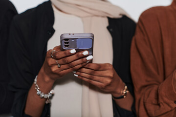 Captured in a close-up moment, a girl in hijab skillfully engages with her smartphone, reflecting a contemporary lifestyle where digital connectivity seamlessly intertwines with cultural expression