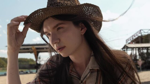 Very handsome guy with long hair poses in a braided cowboy hat for the camera. Close-up 