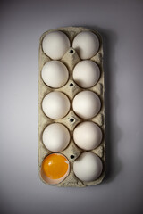 White eggs and egg yolk in a cardboard package on a white background. Top view