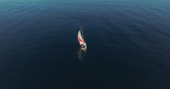 Aerial view. Yacht sailing on open sea at windy day aerial. Sun shine over white sail boat at ocean bay