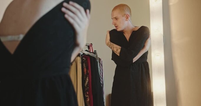 Homosexuality in female dress gently hugging herself in front of mirror