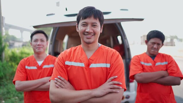  Emergency roadside staffs in safety orange uniform looking at camera and arms crossed.