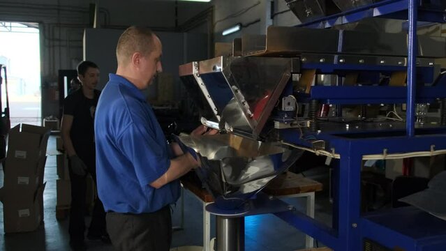 Professional employee works with coffee processing machine. Man makes adjustments as needed to ensure quality of final product