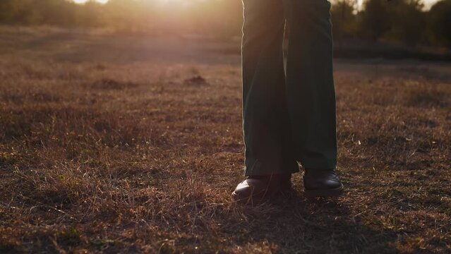 Footsteps of a man in brown leather boots on the grass in the setting sun close-up 