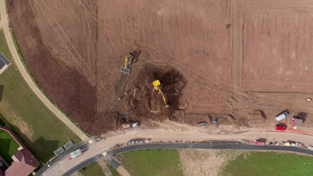 Aerial view of escavator at work on red soil to build new houses in England