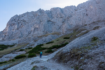 Fototapeta na wymiar Hiker woman with panoramic view of majestic mountain cliff Schartenspitze in untamed Hochschwab mountain region, Styria, Austria. Scenic hiking trail in remote Austrian Alps. Wanderlust, alpine summer