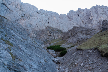 Panoramic view of majestic mountain cliff Schartenspitze in untamed Hochschwab mountain region, Styria, Austria. Scenic hiking trail in shadows in remote Austrian Alps. Wanderlust in alpine summer