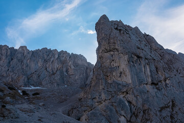 Fototapeta premium Panoramic view of majestic mountain cliff Schartenspitze in untamed Hochschwab mountain region, Styria, Austria. Scenic hiking trail in shadows in remote Austrian Alps. Wanderlust in alpine summer