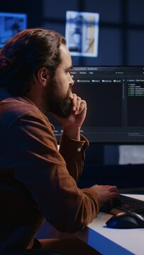 Programmer doing web development during remote job shift in neon lit home office, finishing coding project. IT specialist sitting at computer desk, working on desktop PC, camera B