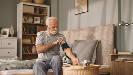 Senior man measuring blood pressure in bed