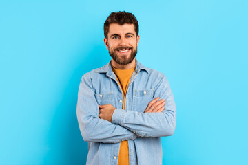 Portrait of cheerful confident young man posing with arms folded