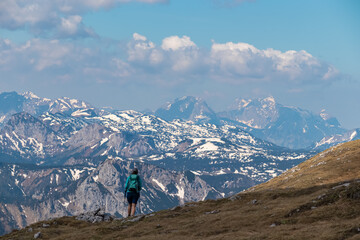 Fototapeta na wymiar Hiker woman with panoramic view from mountain summit Foelzstein in Hochschwab massif, Styria, Austria. Looking at majestic Ennstaler Alps in Gesaeuse in distance. Wanderlust in remote Austrian Alps