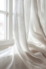 A white curtain hanging in front of a window. Can be used to create a soft and airy atmosphere in interior design