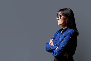 Profile view of middle aged smiling woman, gray background, copy space