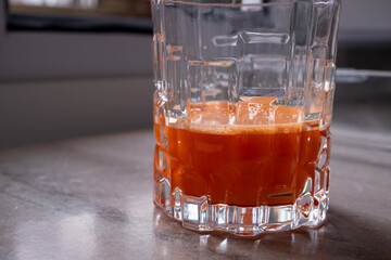 Freshly squeezed carrot juice in a crystal glass glass next to coffee beans