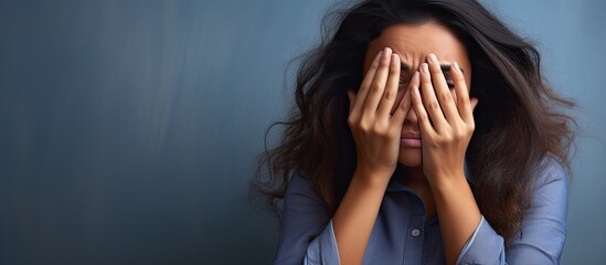 Young hispanic woman at physiotherapist appointment peeking in shock covering face and eyes with hand looking through fingers with embarrassed expression. Creative Banner. Copyspace image