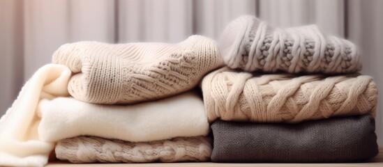 Pile of various woolen knitted blankets sweaters in pastel colors folded on a small round table on...