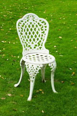 White metal chair on a lush green lawn.