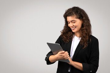 Young businesswoman in black suit using digital tablet, reviewing important documents or chatting online with clients