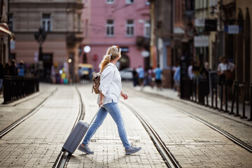 Woman tourist with suitcase walks across city street. Secure  journey with reliable travel insurance