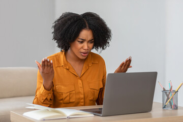 Perplexed African American woman with natural curly hair in a mustard blouse reacts to something