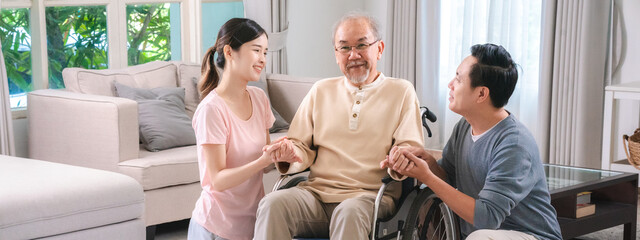 Gentle daughter and son are taking care and support help their retired and elderly father or dad on wheelchair at home, positive energy for senior patient, bonding between family, disability caregiver
