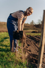 Earth on a shovel. The gardener digs the soil with a shovel in the garden in spring, black soil on the farm.