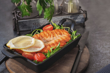 Grilled salmon steak with arugula salad, tomatoes and shallots. The concept of healthy eating, diet, low calorie