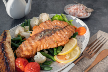 Grilled salmon steak with vegetables - cauliflower and broccoli, tomatoes and shallots. Healthy eating concept.