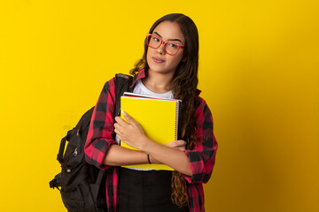 Fototapeta premium Woman wearing glasses, plaid shirt holding books and notebook with a backpack on her back