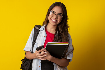 Fototapeta premium Woman, wearing glasses, denim shirt holding books and notebook with a backpack on her back