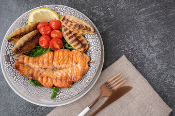 Grilled salmon steak with vegetables - cauliflower and broccoli, tomatoes and shallots. Healthy eating concept. Copy space. Top view, flat lay.